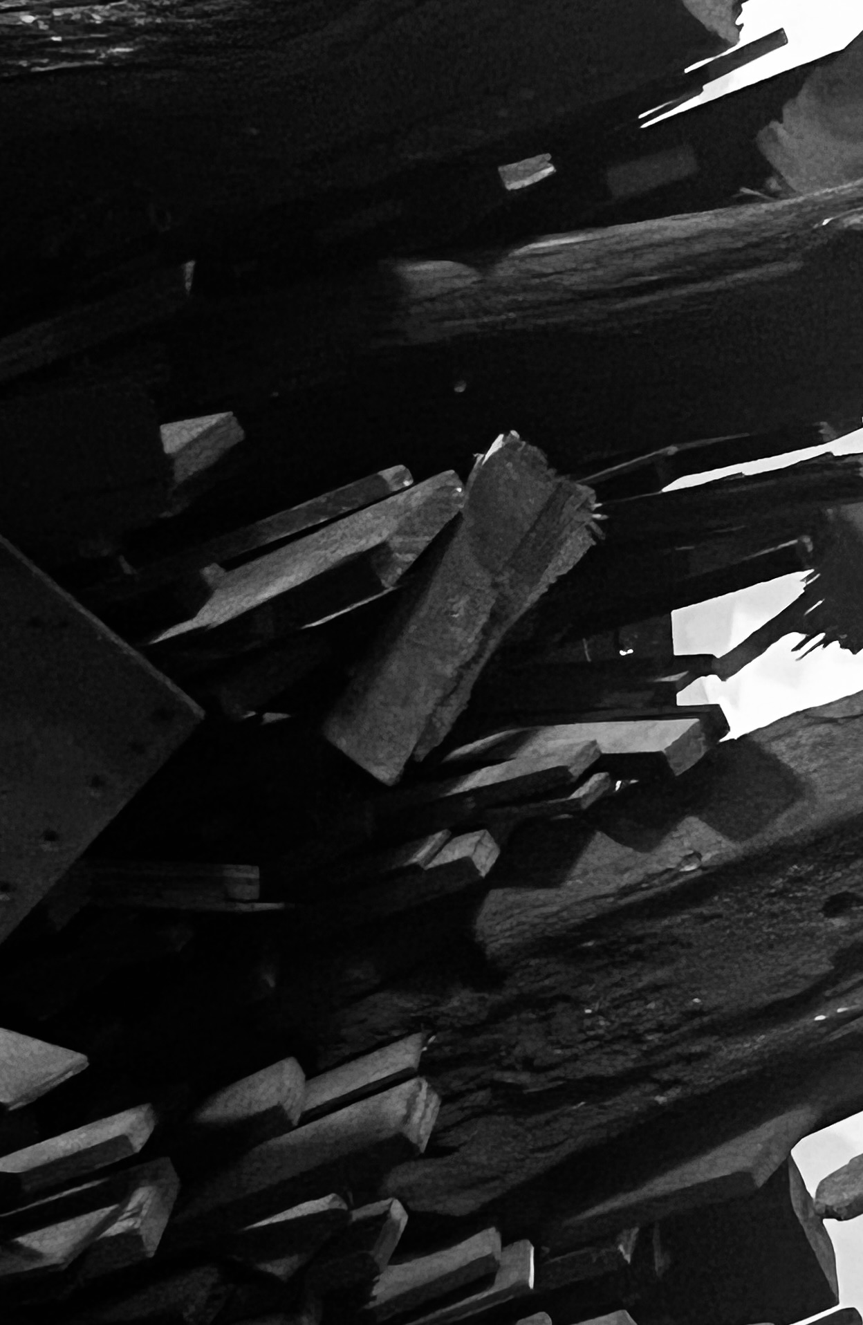 Abstract black-and-white close-up of broken wooden fragments and angular openings.