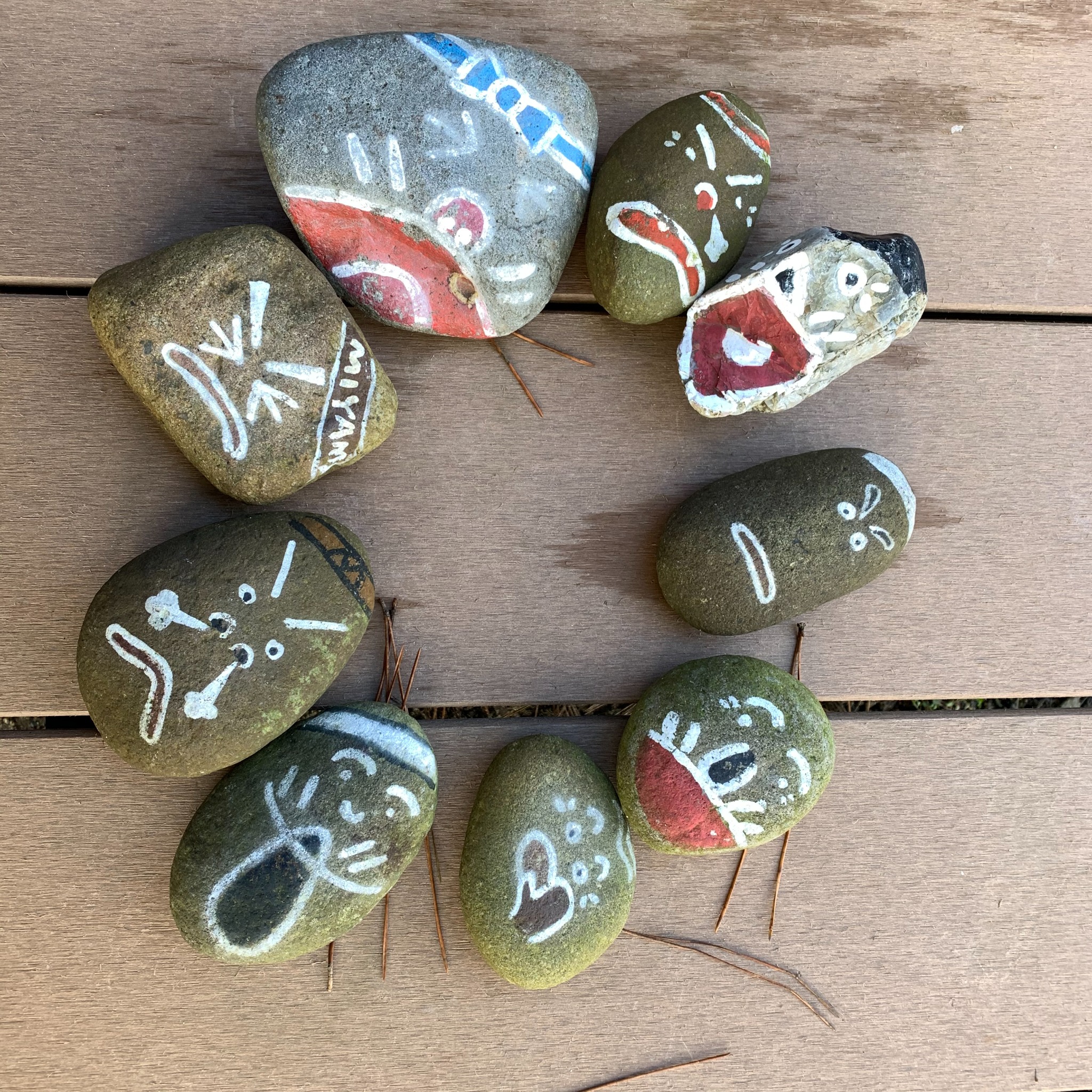 A circle of hand-painted stones arranged on a wooden surface.