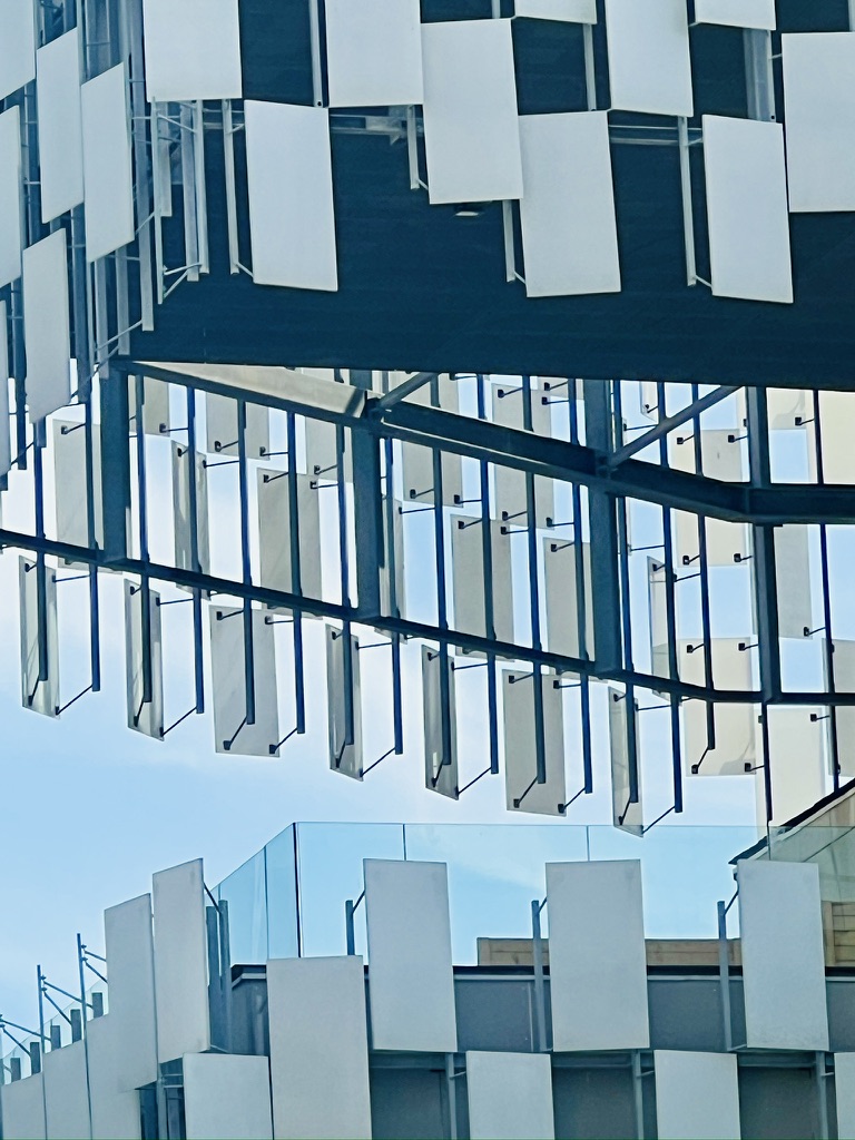 Vertically transformed architectural photograph in blue-grey and white, built from repeated structural fragments.